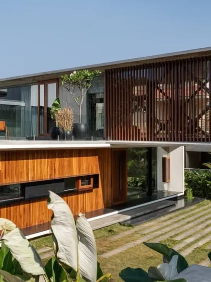 This view highlights the interplay of solid and void. The upper level features a wooden screen that provides privacy and filters light, while the ground floor opens up to the garden, demonstrating our focus on creating layered architectural experiences.
