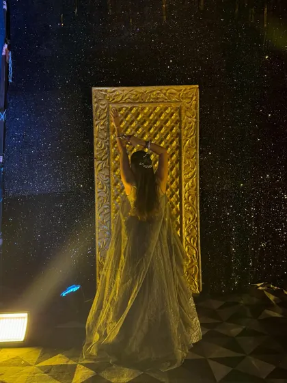 An artistic pose, reaching up towards a golden door on a starry stage. This shot has a magical, fairytale quality.