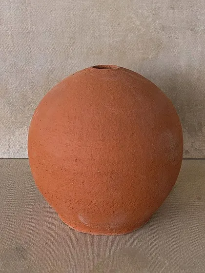 A simple, round terracotta vase. Sometimes the most basic forms are the most beautiful, showing the pure color and texture of the clay.