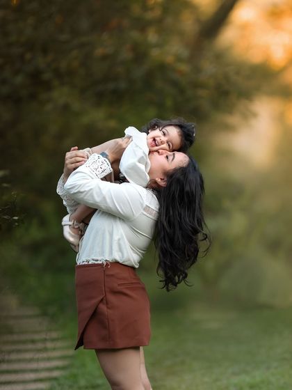 Lifting her little one up to the sky! This photo is filled with so much joy and love. The warm, golden light of the evening makes this mother-daughter moment even more special.