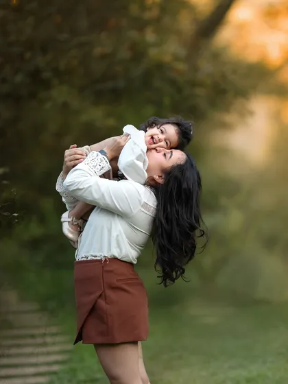 This playful lift between a mother and her baby is just pure joy. I love capturing these energetic, happy moments during our outdoor family photoshoots.
