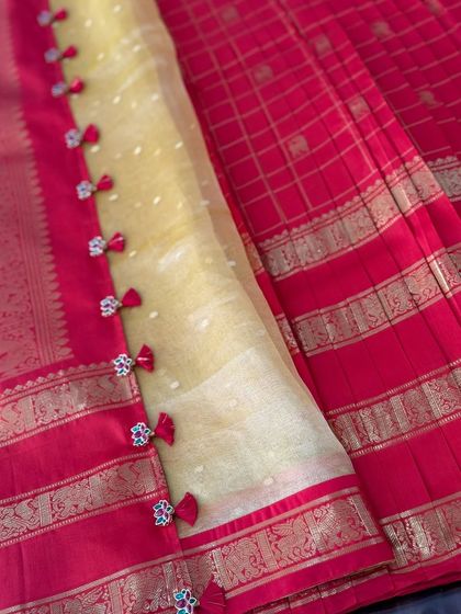 The beautiful border of the sheer yellow dupatta, adorned with matching Jadau pendants and red tassels.