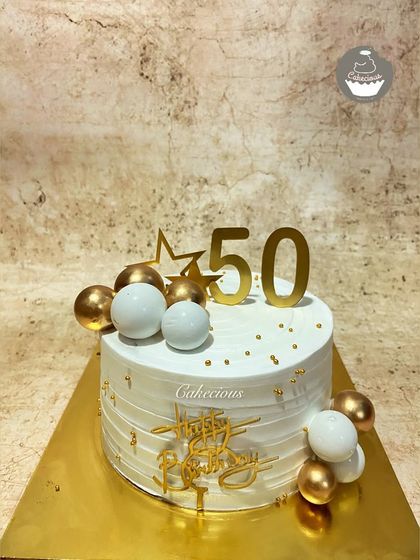 Celebrating the golden 50th birthday with a classic and elegant cake. The white and gold theme with simple sphere decorations is timeless and sophisticated.