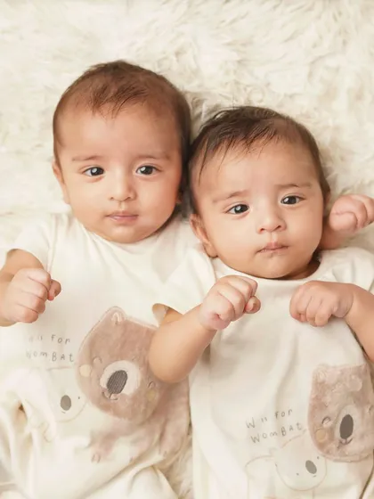 The twins look like they're ready to take on the world together. Their matching outfits and synchronized poses are incredibly cute.