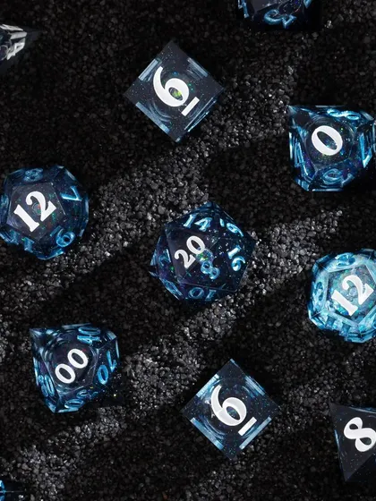 A similar setup with blue dice on black sand, creating a cool, cosmic feel. The scattered arrangement gives the impression of a newly discovered galaxy of dice.
