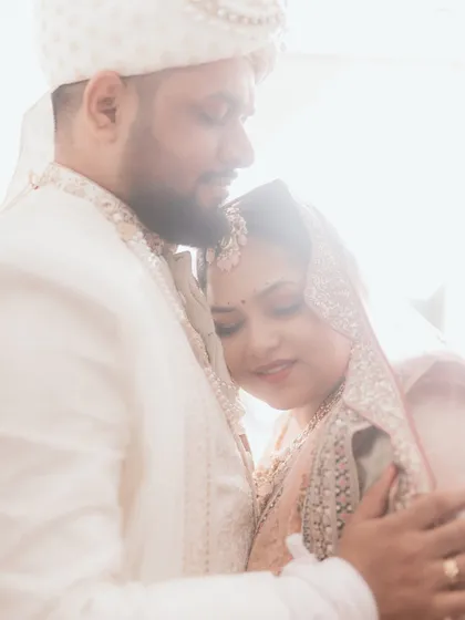 A soft, light-filled embrace between the bride and groom. Her head rests on his chest, a picture of comfort, trust, and quiet love. The dreamy backlighting makes this moment feel even more magical.
