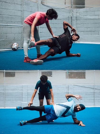 A coach assists two athletes with a challenging side plank variation, a key exercise for core stability and hip strength. This hands-on correction ensures proper muscle engagement and safe execution.