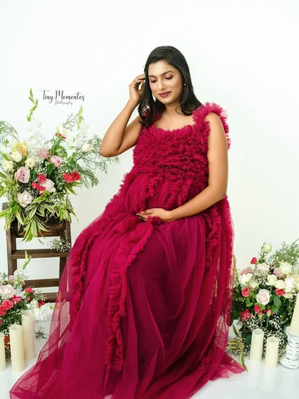 Seated amidst flowers and candles, the rich texture of the magenta gown adds a touch of romantic luxury to this beautiful maternity portrait.