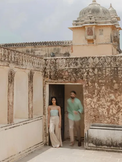 A creative shot using motion blur to add a dynamic feel. The bride stands in sharp focus while the groom walks past, symbolizing their journey together in a visually interesting way.