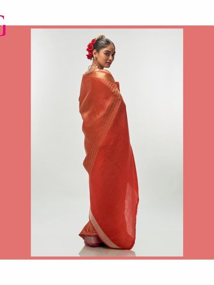 The back view of the orange silk linen saree, showing its beautiful drape and the way the color catches the light.