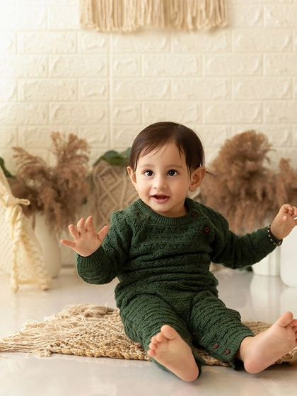 A wide shot of the boho-themed cake smash setup, showing the baby boy sitting happily before the cake arrives.