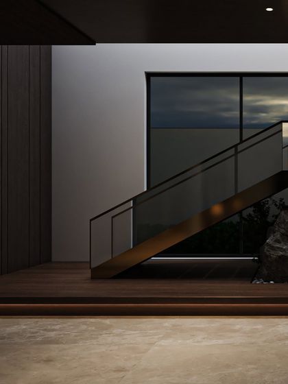 A close-up of the staircase and indoor garden, showing the contrast between the sleek glass railing, the warm wood, and the organic forms of the rocks.