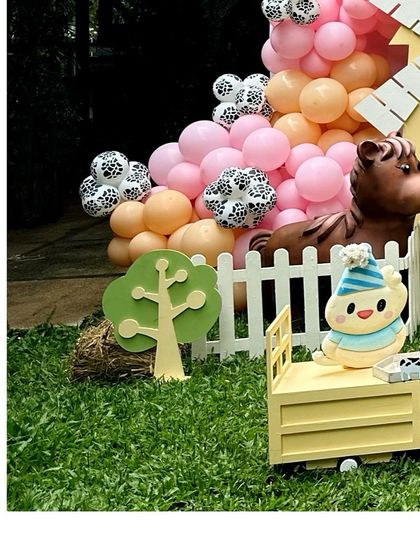 A corner of the farm party, with a horse prop, a white picket fence, and a colorful balloon garland.