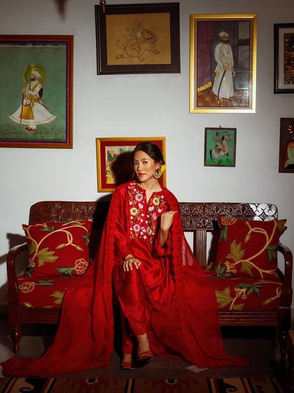 A regal portrait for Baavli, with the model seated on a vintage sofa. The composition is rich with color, texture, and traditional art.