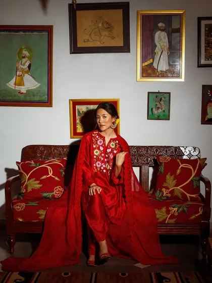 A regal portrait for Baavli, with the model seated on a vintage sofa. The composition is rich with color, texture, and traditional art.