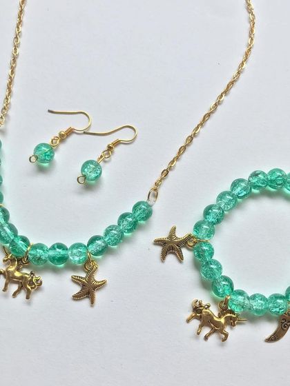 A different arrangement of the green charm necklace and bracelet set, showing its vibrant colour and playful design.