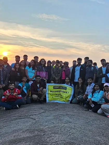 Our group proudly holding the "Accomplished" banner after the Uttari Betta sunrise trek.