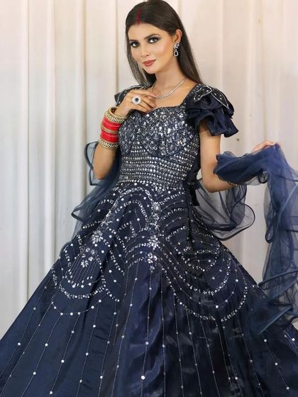 A client looking beautiful in a navy blue sequined gown. The ruffled sleeves and sparkling details make it a perfect outfit for a reception or cocktail party.