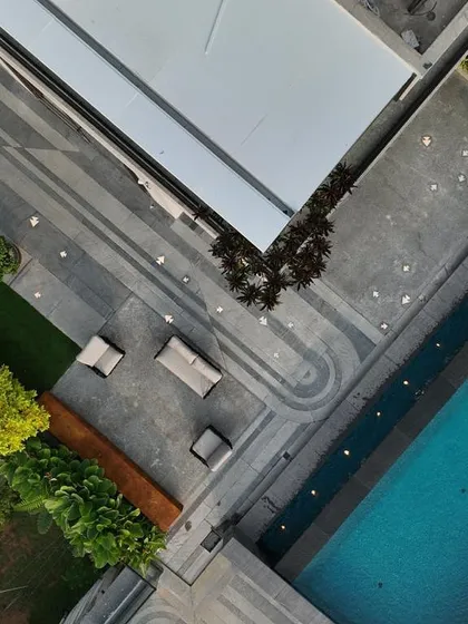 An aerial view of a large residential property, showing a lap pool integrated into the landscape design. The pool is surrounded by a paved deck, lawn, and seating areas, making it the heart of the outdoor living space.