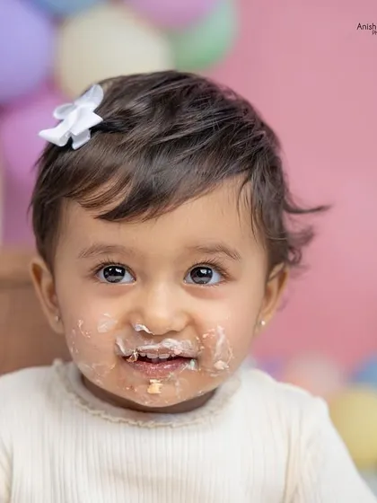 That cake-covered smile says it all! A close-up portrait capturing the pure joy of a first birthday cake smash.