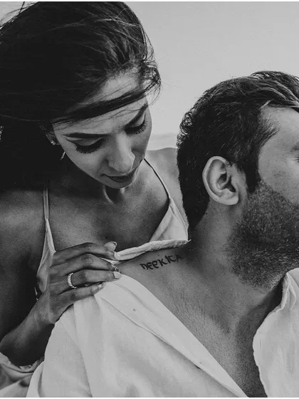 A beautiful black and white shot focusing on a personal detail, the bride-to-be pointing to her partner's name tattooed on his neck.