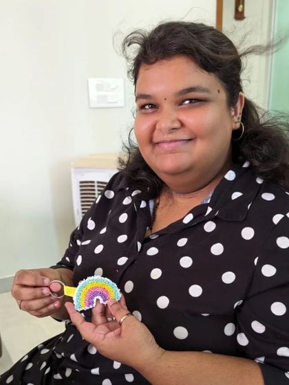 A happy crafter with her pastel rainbow charm, showcasing a softer color palette.