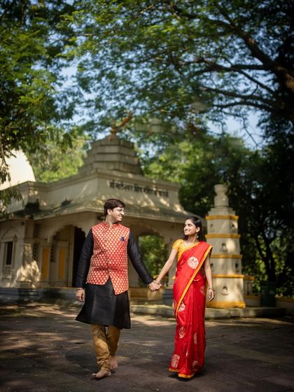 A couple in vibrant traditional Indian attire walking hand-in-hand on temple grounds. This captures a blend of cultural heritage and natural beauty.