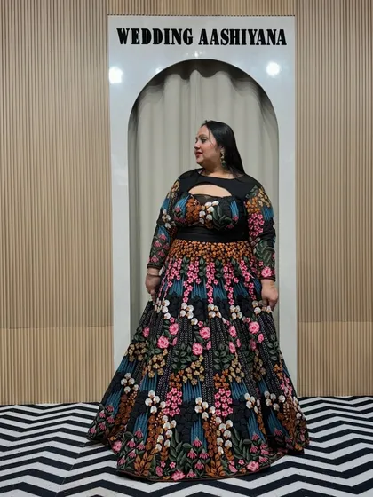 A beautiful plus-size client in a stunning black lehenga with colorful floral embroidery. The keyhole neckline and full sleeves make it a stylish and comfortable choice for any celebration.