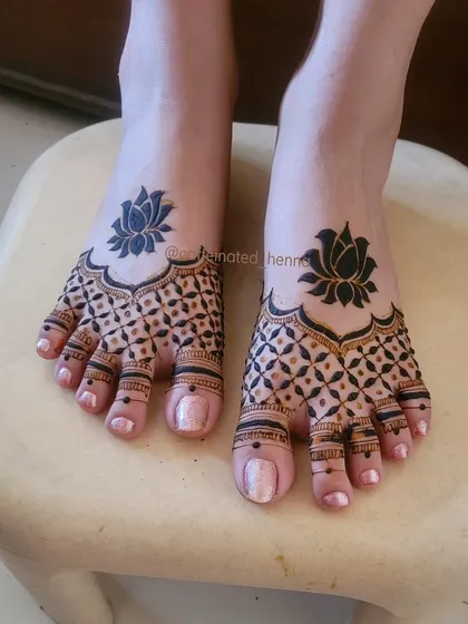 Don't forget the feet. This is a clean and dainty feet henna design, featuring bold lotus motifs that stand out against a delicate grid pattern. It’s a perfect complement to any bridal or party look.