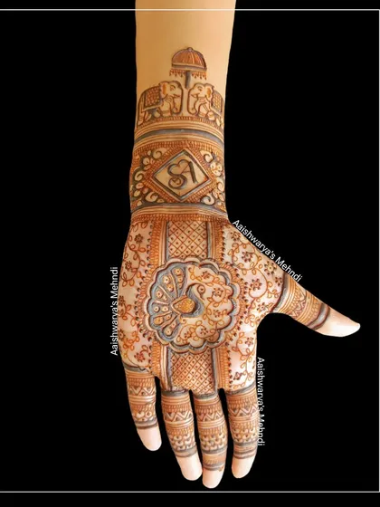 This design features a central peacock mandala on the palm, with elephant motifs and a personalized initial on the arm.