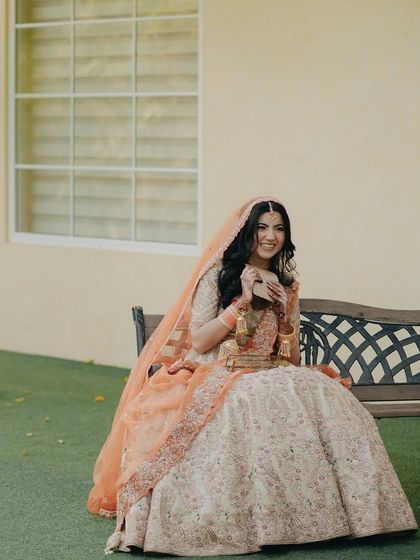 A happy bride enjoying a lighthearted moment, her genuine smile captured as she sits on a bench in a garden setting.