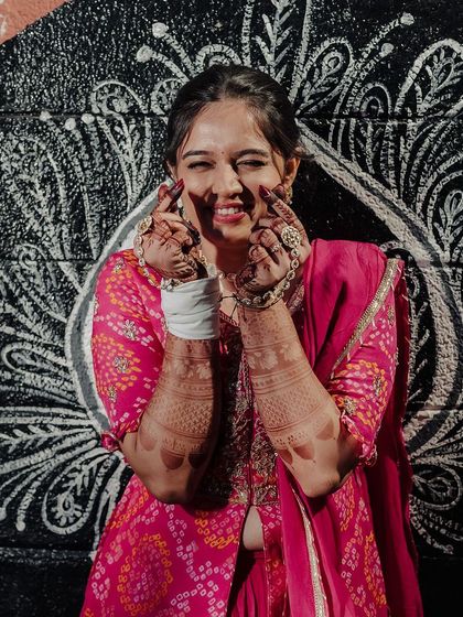 A playful and happy bride, her smile lighting up the frame as she shows off her mehendi.