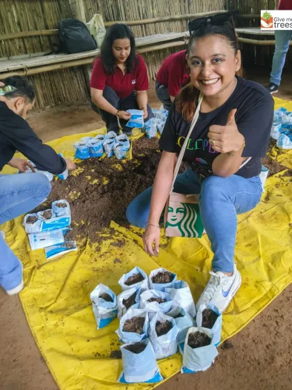An employee from KPMG gives a thumbs-up while preparing sapling bags at our Neem Karoli Temple site. These activities are a fun, hands-on way for corporate teams to learn about the nursery process and contribute to our greening efforts.