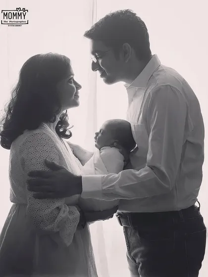 A classic and intimate family portrait. This black and white photo captures the loving gaze between new parents as they hold their baby together.