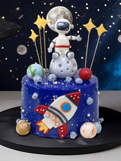 An out-of-this-world space cake, featuring an astronaut on the moon, a rocket ship, and a galaxy of stars and planets. Perfect for a future space explorer.