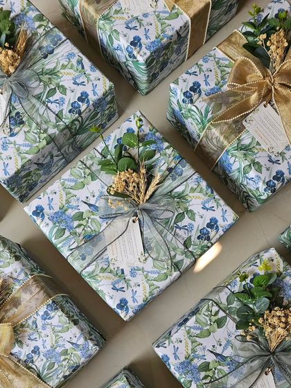 An overhead view of the custom-wrapped wedding favors. The consistent floral paper creates a cohesive look, while the different ribbons add a touch of variety.