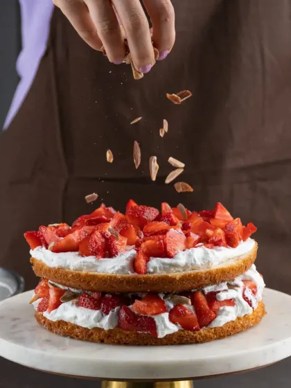 We believe in being generous with our ingredients. Here, we're adding a sprinkle of toasted almonds to our Strawberry Almond Gateau, which is already loaded with fresh strawberries.