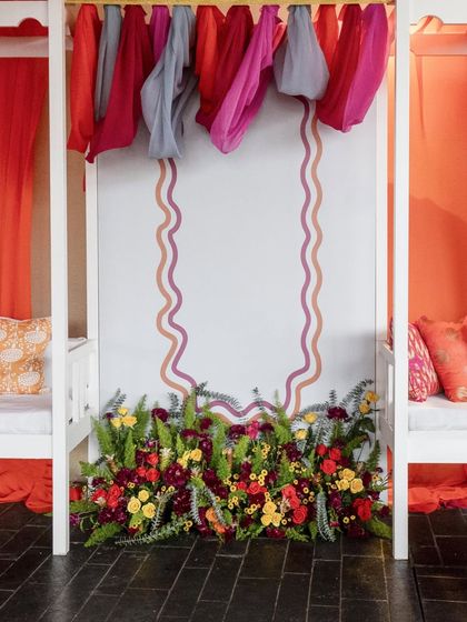 A symmetrical view of a decor element, featuring a floral arrangement at the base of a wall with elegant, wavy painted borders.