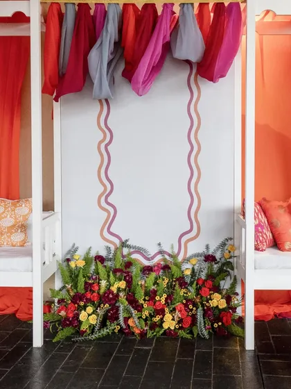 A symmetrical view of a decor element, featuring a floral arrangement at the base of a wall with elegant, wavy painted borders.