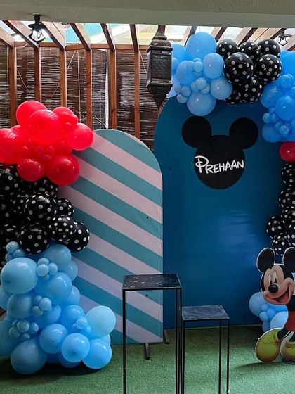 A classic Mickey Mouse theme featuring the iconic mouse ears silhouette on the backdrop. The decoration uses a bold color palette of red, blue, and black with polka-dot balloons and a Mickey Mouse balloon sculpture.