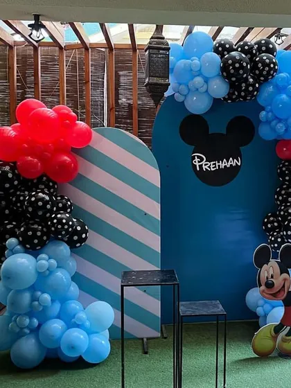 A classic Mickey Mouse theme featuring the iconic mouse ears silhouette on the backdrop. The decoration uses a bold color palette of red, blue, and black with polka-dot balloons and a Mickey Mouse balloon sculpture.
