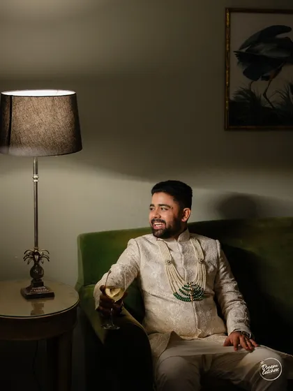 A relaxed portrait of the groom enjoying a quiet moment with a drink before the festivities begin.