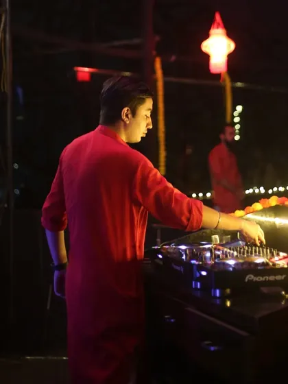A side profile shot of me at the decks during a night event, with festive lights in the background.