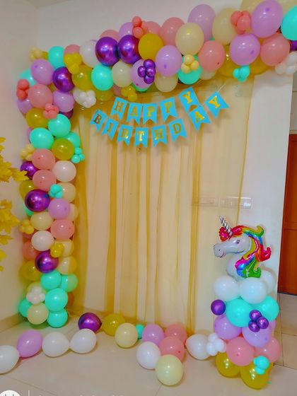 A simple and colorful unicorn-themed birthday decoration. This setup includes a pastel balloon arch and a unicorn balloon column, perfect for home celebrations.