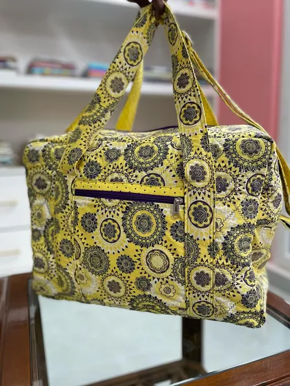 Learn to make your own durable and stylish quilted travel bags in our classes. This custom-made bag features a vibrant pattern, sturdy construction, and practical details like an exterior zip pocket.