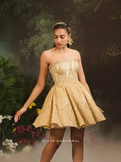 The Jules Dress is my vision of modern celebration. I designed this strapless cocktail dress with a structured corset and a flared skirt, covering it in geometric patterns of gold and silver embellishments for a truly radiant effect.