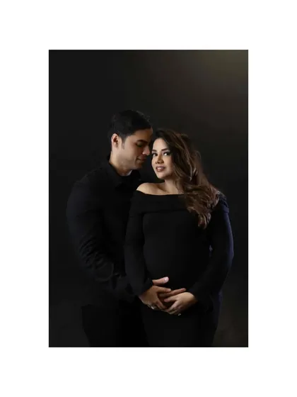 An intimate and classic couple portrait. The dark outfits and background create a moody, dramatic feel, while the close embrace and her gentle look towards the camera make it a powerful and connecting image.