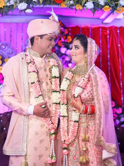 A sweet moment between the bride and groom during their Jaimala ceremony. Their pastel pink outfits are perfectly coordinated, and their smiles are infectious.