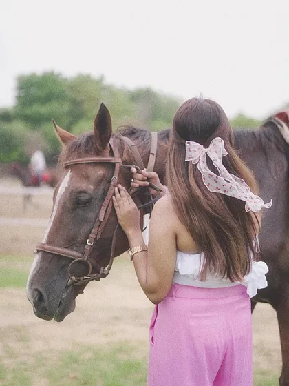 A rider gently adjusts the horse's bridle, a small act of care that builds trust and strengthens the bond between them.