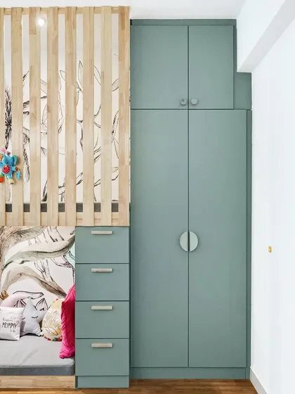 A detail shot of the custom-built loft bed and storage unit. The combination of the wooden slide, sage green cabinets, and playful wallpaper creates a cohesive and stylish design.